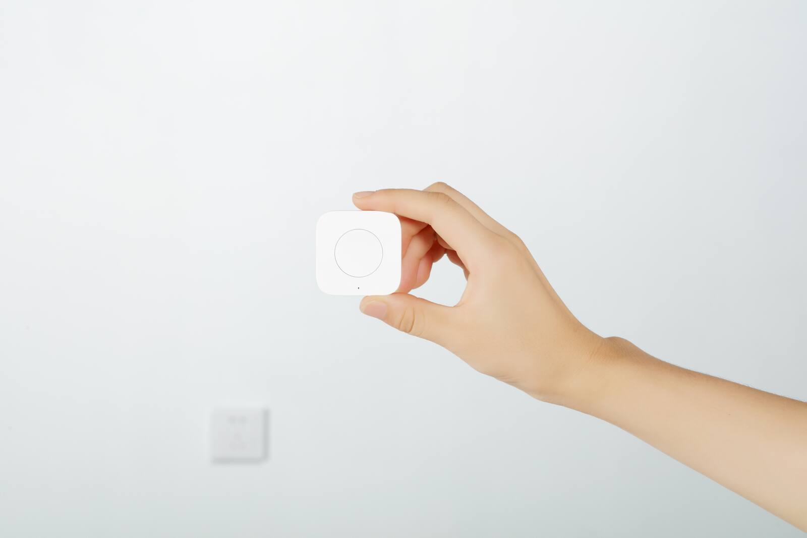 Wireless Aqara button held in front of a wall switch