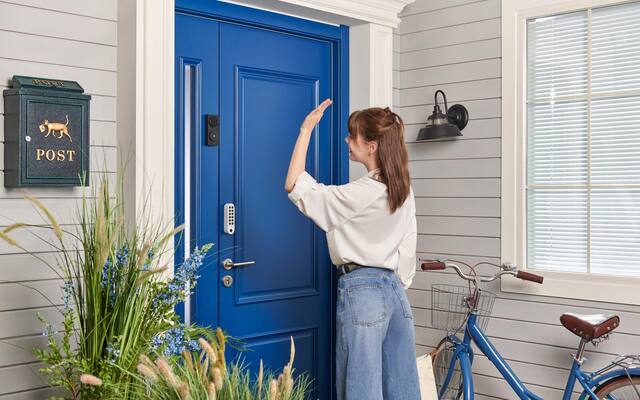 Aqara G410 video doorbell installed beside a blue front door as a visitor approaches