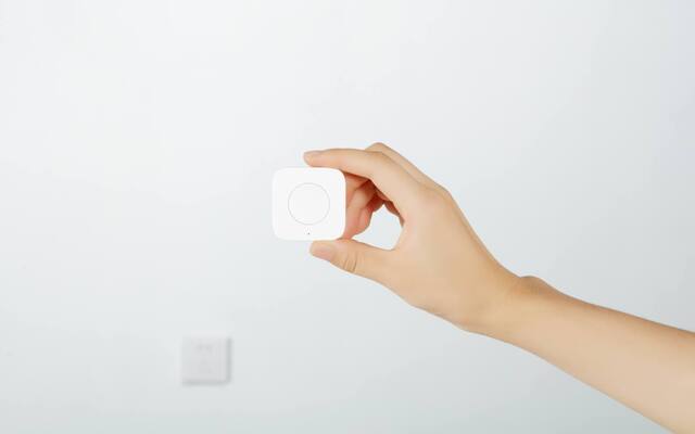 Wireless Aqara button held in front of a power socket