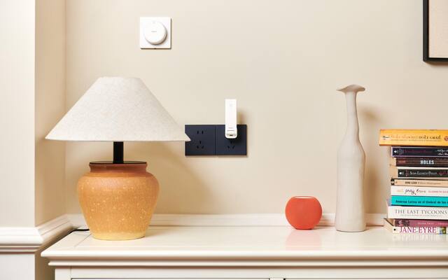 Aqara Hub M100 plugged into a wall outlet in a furnished room
