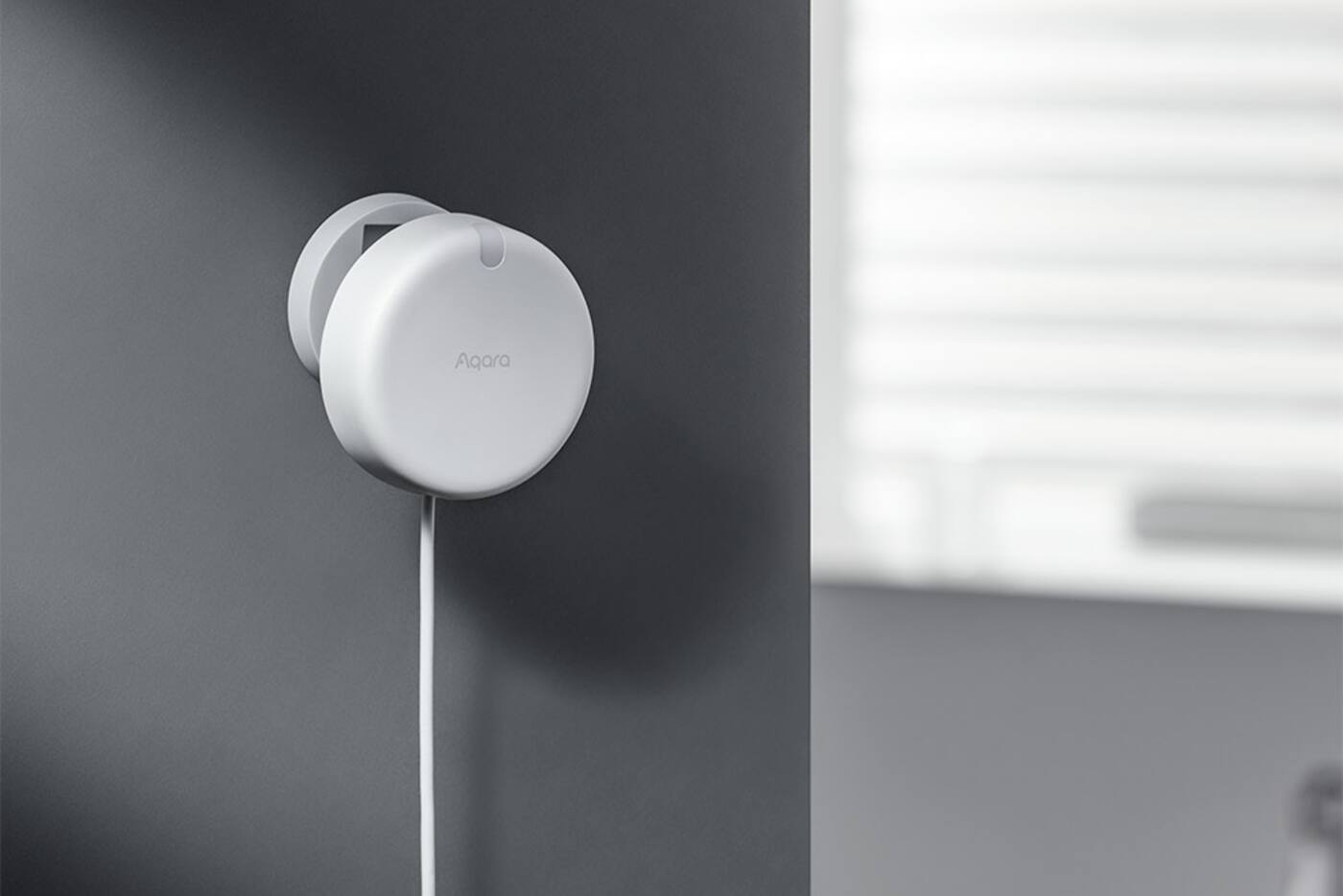 White Aqara FP2 presence sensor mounted high on a wall and angled into a room