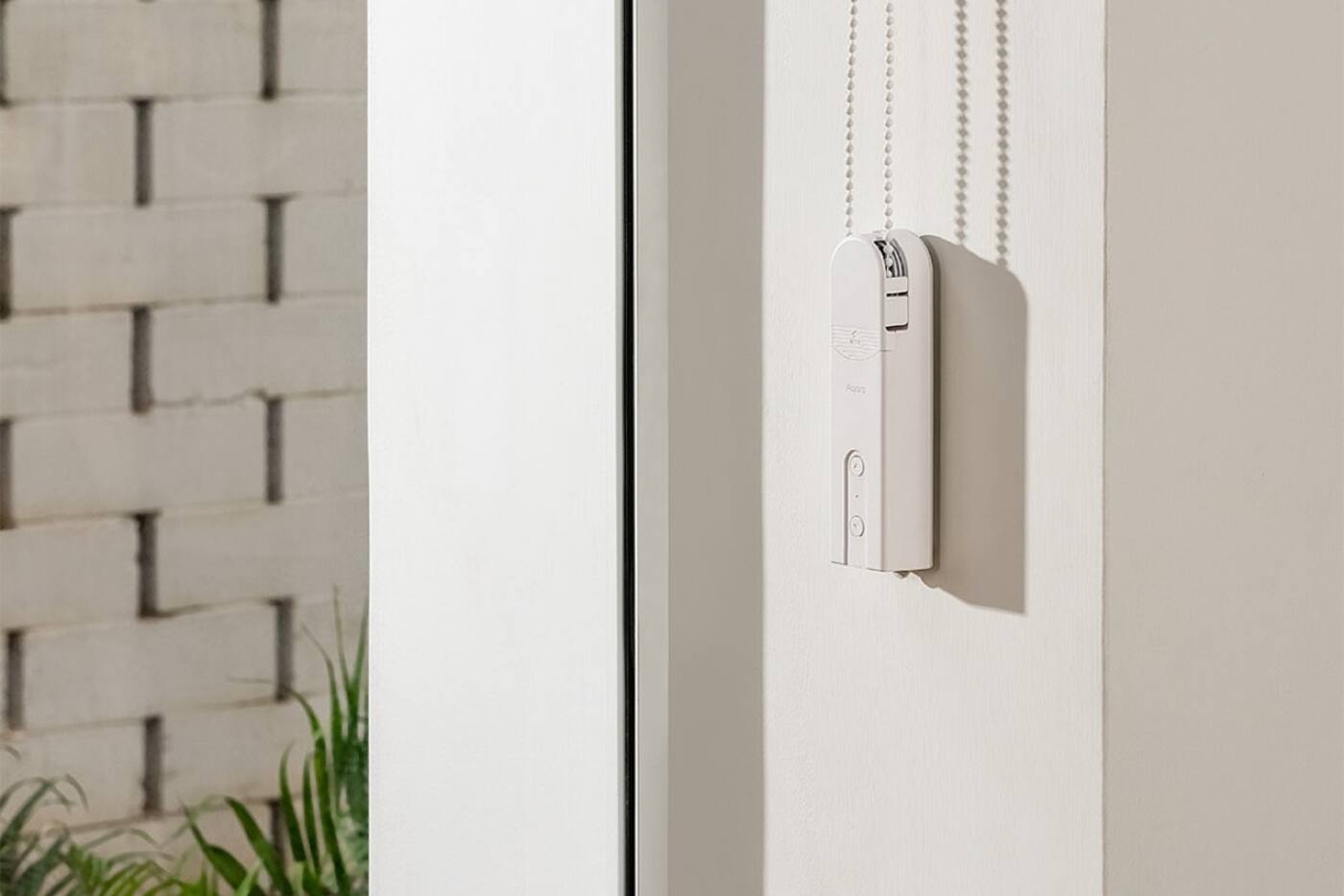 Aqara Roller Shade Driver E1 mounted beside a white beaded blind chain