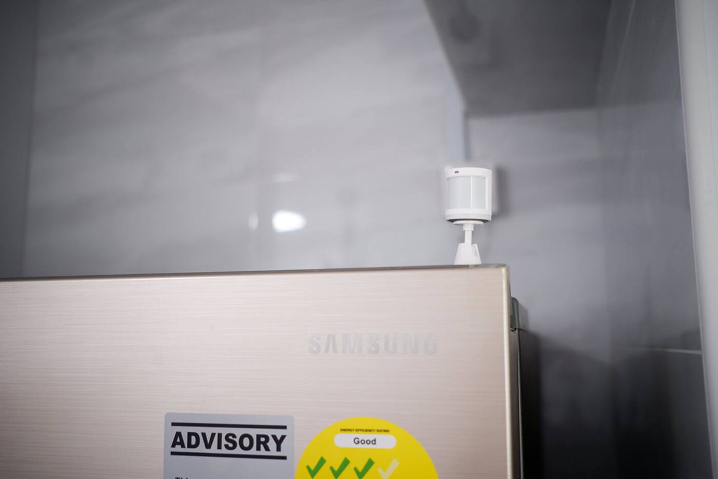 Aqara motion sensor mounted above a refrigerator in a kitchen