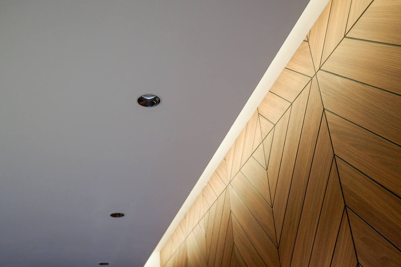 Recessed downlights and concealed cove lighting illuminating a timber wall