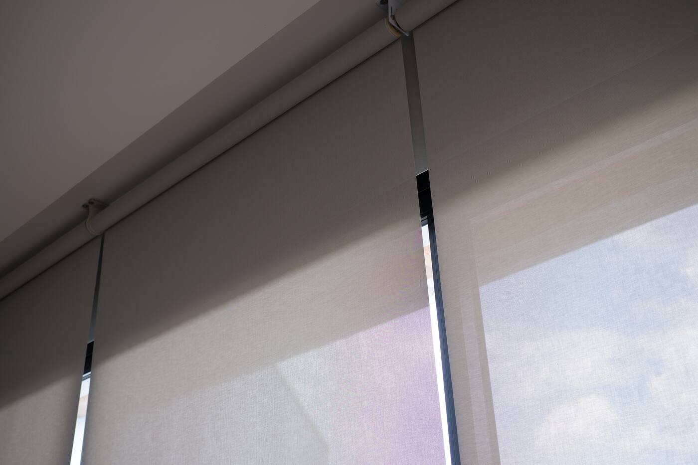 Close view of roller blind tracks aligned across a wide window