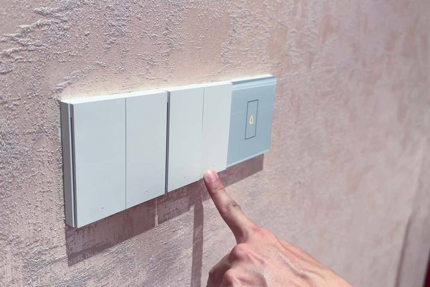 Person pressing a wall-mounted smart light switch