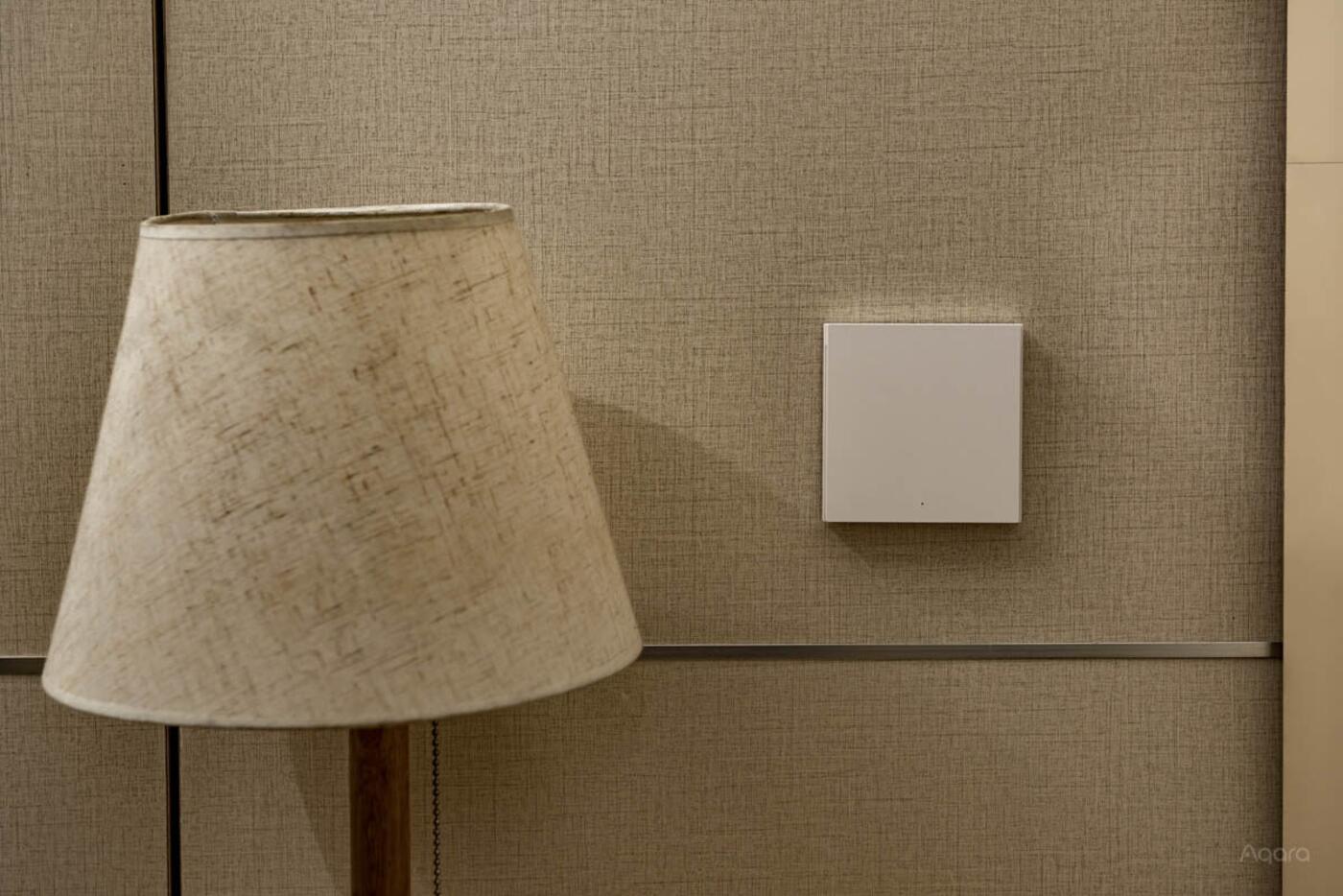 Dark Aqara H1 smart wall switches installed on a wood-panelled wall