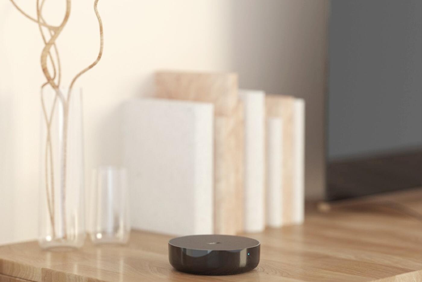 Round Aqara hub positioned openly on a table in the same room as a television