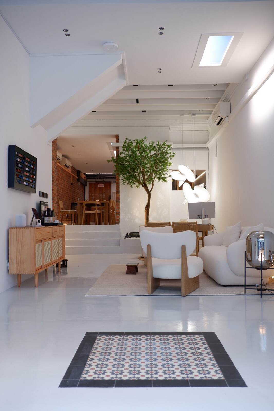 The shophouse hall of the Experience Centre — heritage floor tiles, indoor maple, lounge and skylight
