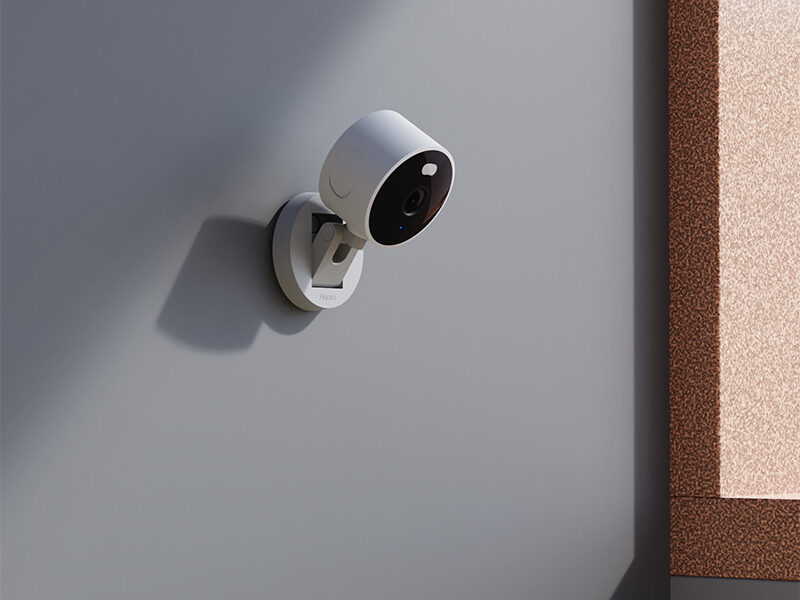 Aqara Camera G100 in white, wall-mounted indoors on a grey wall