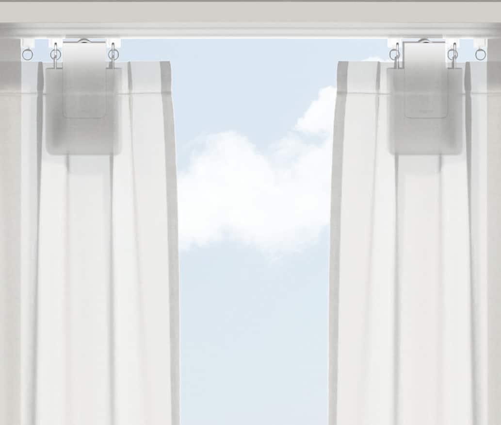 Aqara Curtain Driver E1 mounted on a track behind sheer white curtains, with blue sky beyond the window