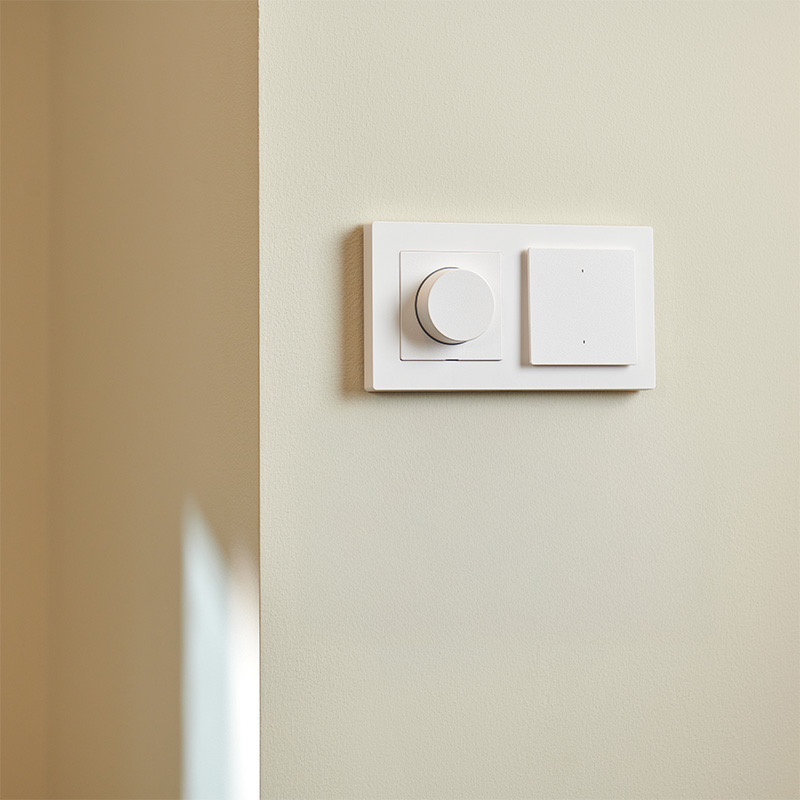 Aqara Dimmer Switch H2 mounted beside a wireless switch on a cream wall