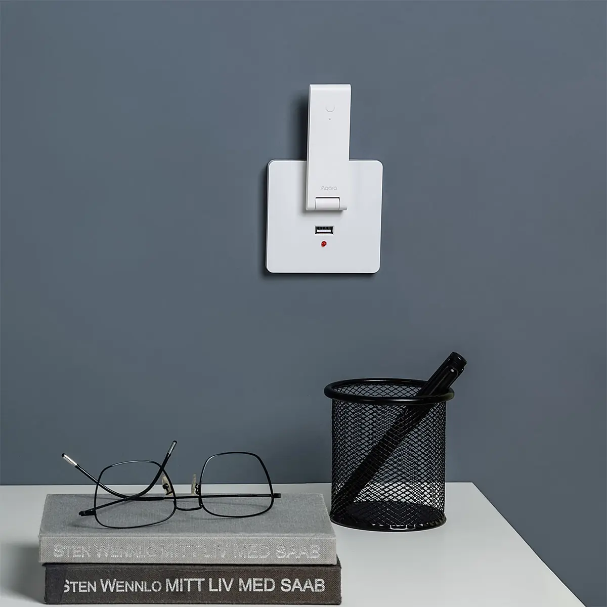 Hub E1 plugged into a wall USB socket above a desk with books and glasses