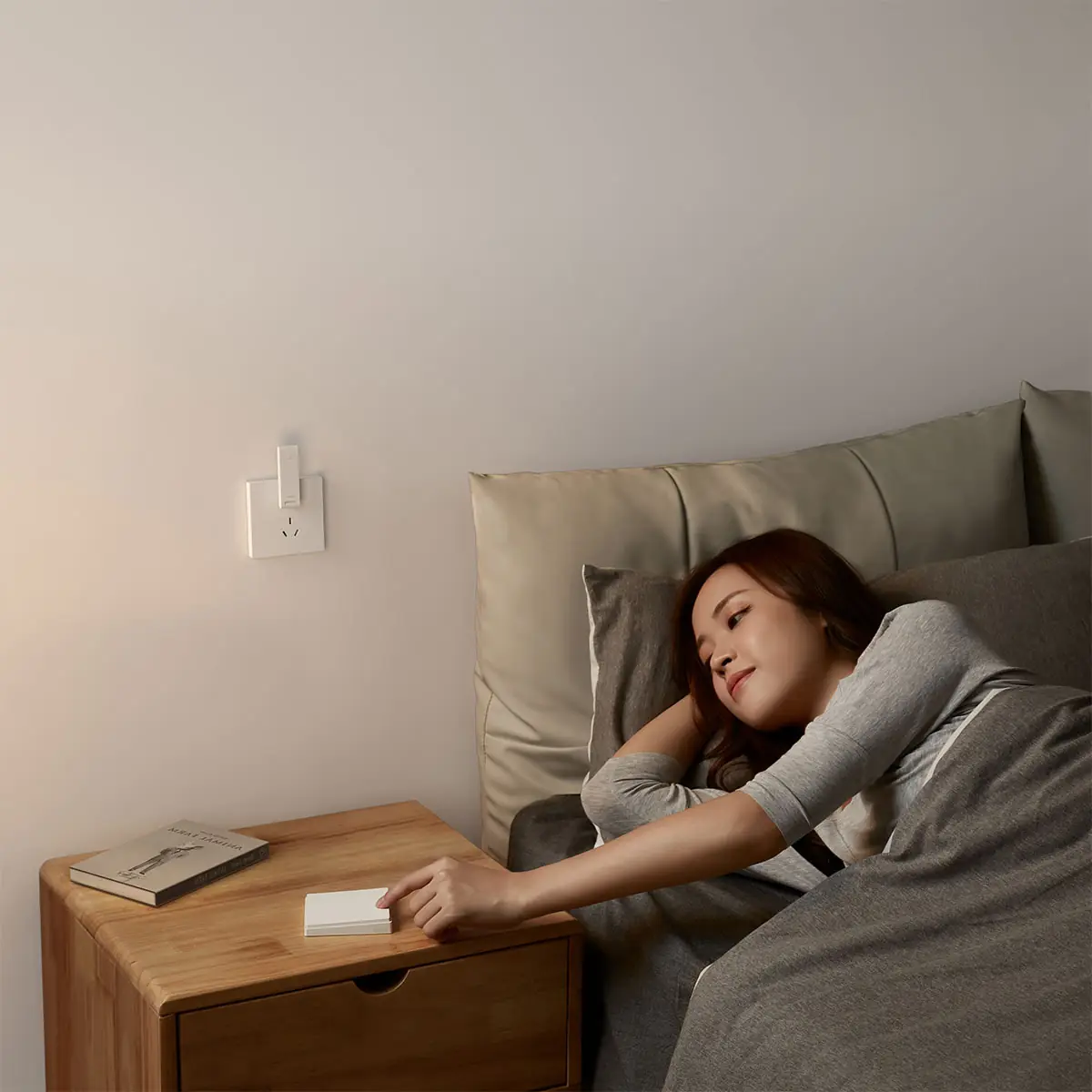 Hub E1 in a bedroom wall socket as someone reaches for a bedside control