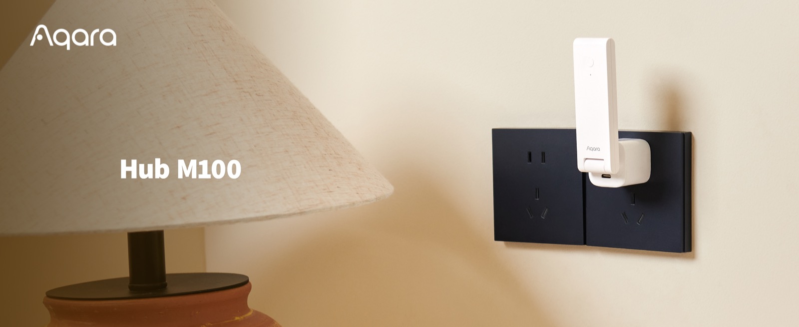 Aqara Hub M100 plugged into a wall socket beside a bedside lamp
