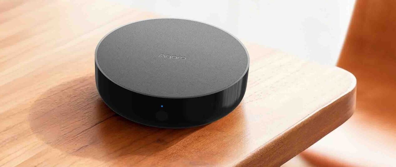 Aqara Hub M200 sitting on a warmly lit wooden table beside a wooden chair