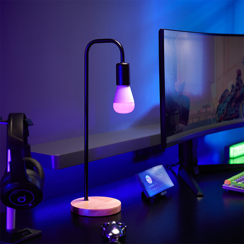 LED Bulb T2 lighting a desk lamp in vivid magenta beside a monitor and headphones