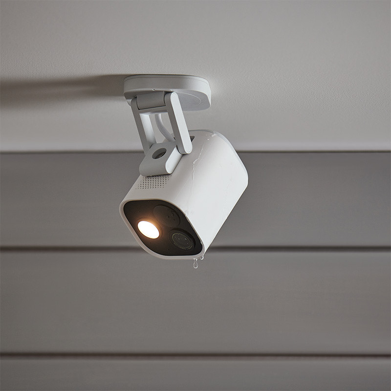 White G5 Pro mounted under an eave with its warm spotlight on and a rain droplet on the housing