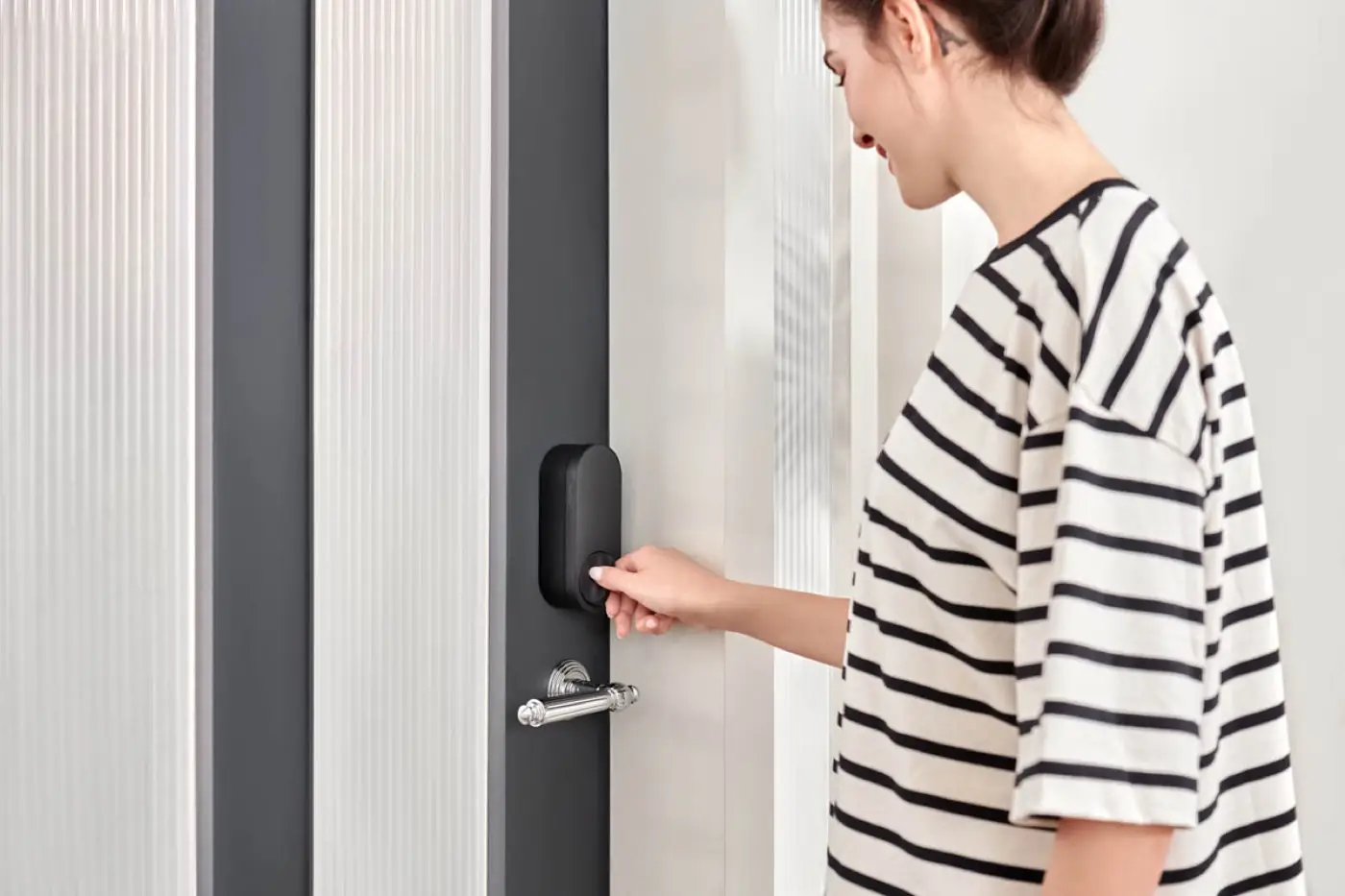 A person turning the Aqara U200 thumbturn on a reeded-glass door to lock it