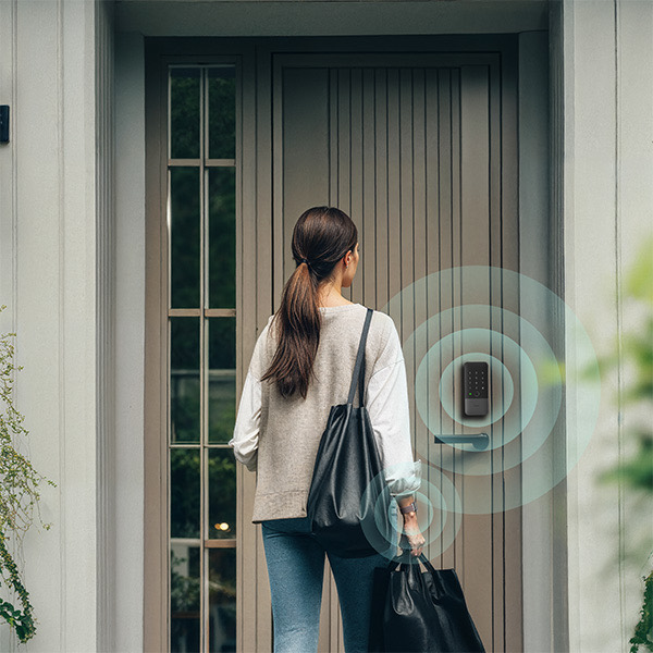 Person walking up to a front door with hands full as the U400 senses their approach
