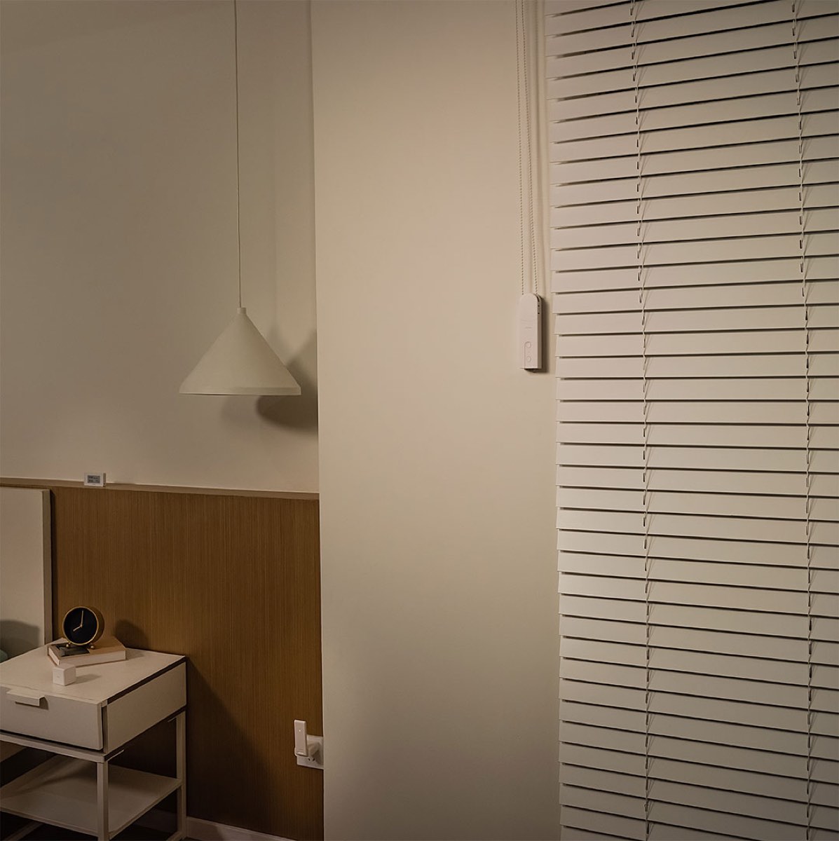 Roller Shade Driver E1 mounted beside a blind in a dim, warmly lit bedroom