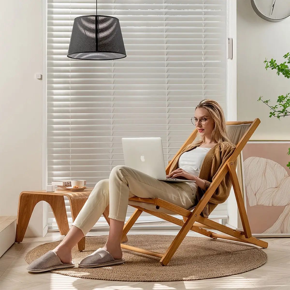 Person relaxing with a laptop in a bright room, daylight filtering through motorised shades