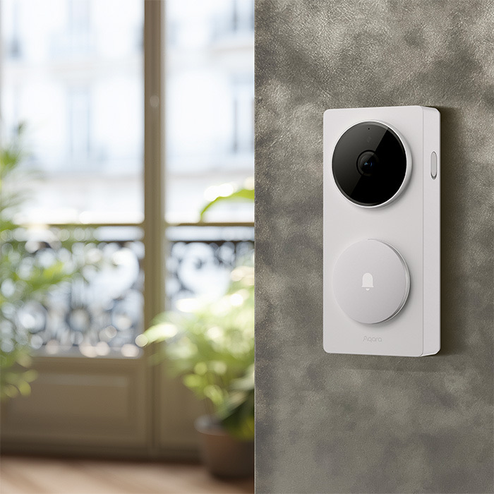 Aqara G410 doorbell in white, mounted on a textured wall beside a bright window