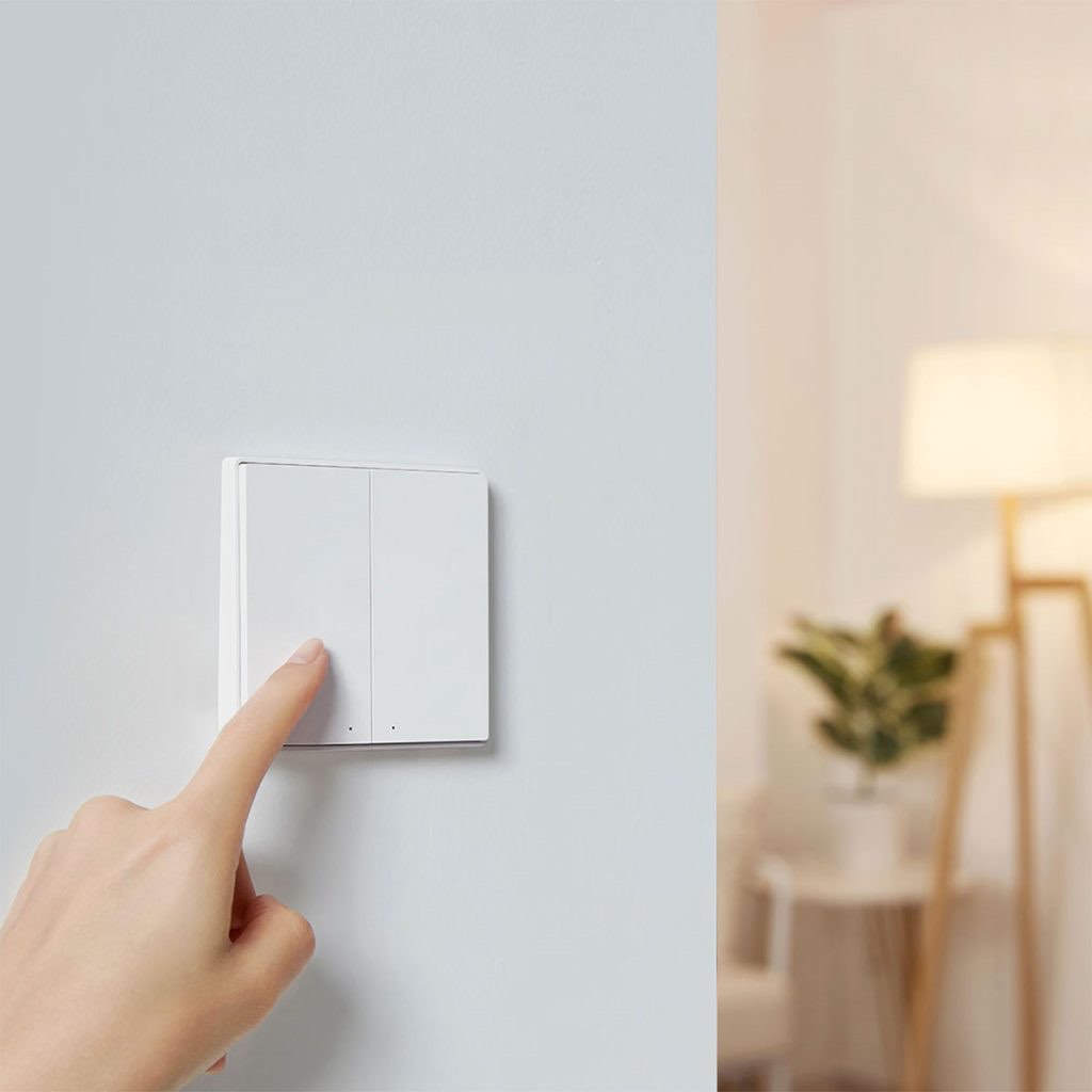 A finger pressing the D1 rocker switch with a warm floor lamp glowing beyond