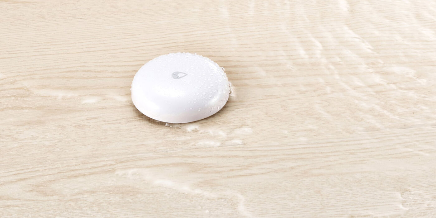 Aqara Water Leak Sensor T1 resting on a wet wooden floor